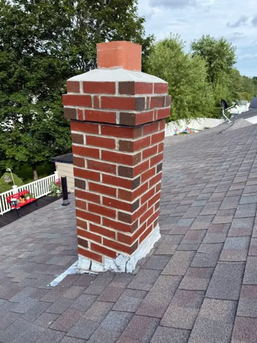 The same chimney fully rebuilt by All Chicago Construction with new brickwork, a fresh crown and a cap