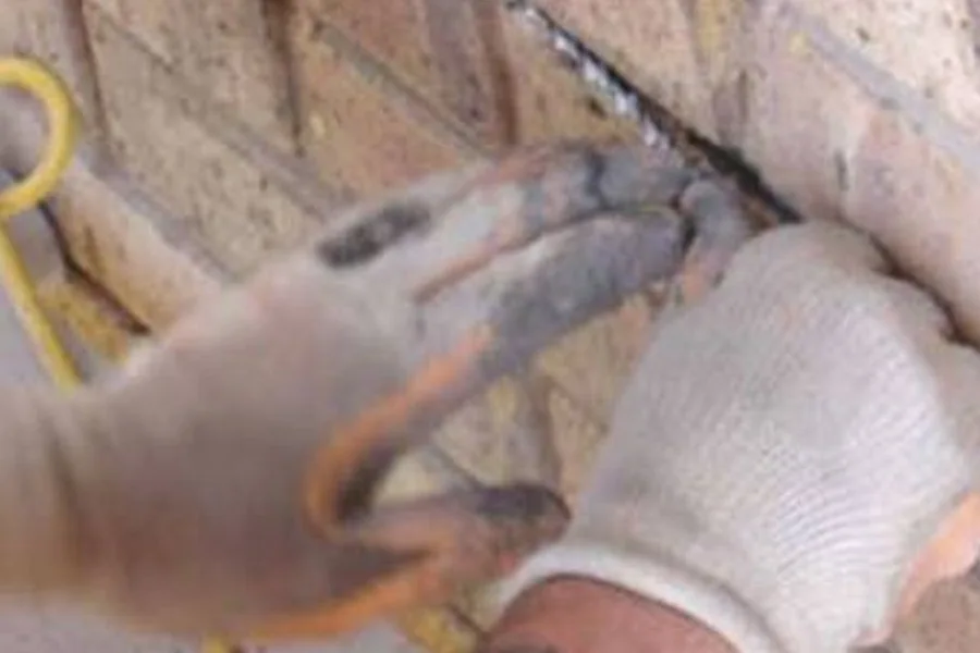 A worker repairing and repointing a cracked foundation wall